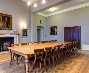 A grand council room with a historical boardroom table.