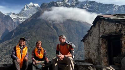 Andrew sat on wall with two people in the Himalayas