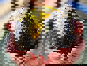 Hands holding a black and yellow globe.