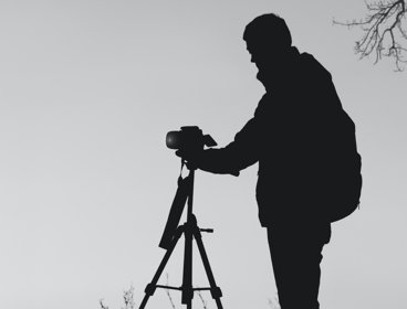 Person outside setting up a camera on a tripod