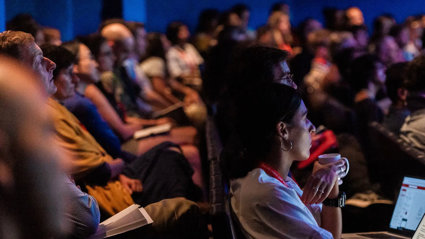 People sat in a theatre with laptops.