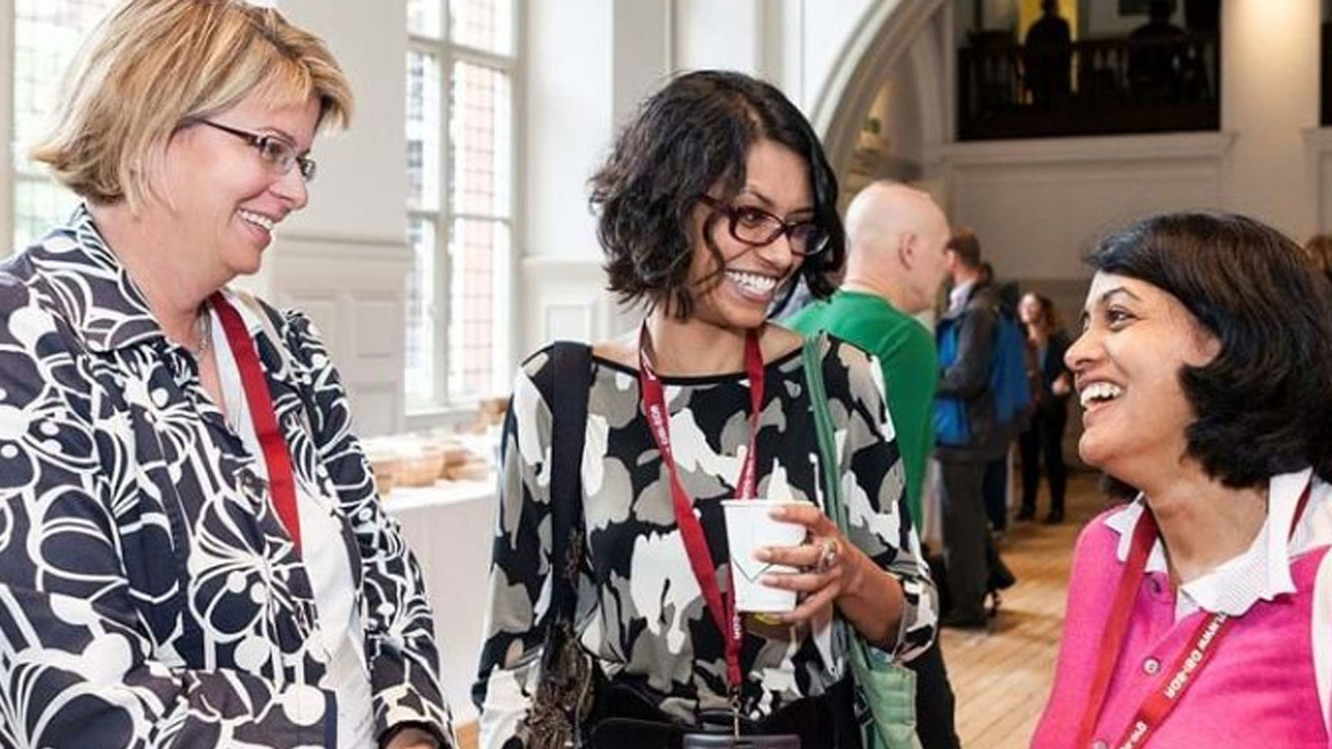 Three people chatting while attending an informal drinks reception in the Main Hall at the Society.