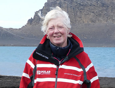 Anne Strathie posing for a photo in front of the natural harbour on Deception Island.