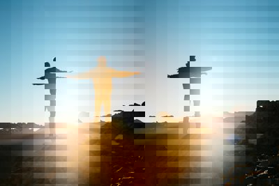 Person standing on a hill with arms outstretched