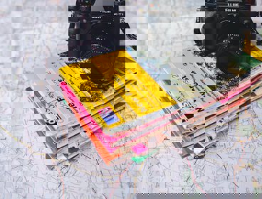 A pile of Ordnance Survey maps and a camera on top of a map