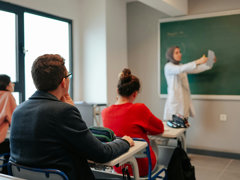 Three students in a university class listen to the teacher