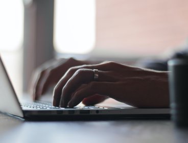 Person typing on a laptop keyboard.