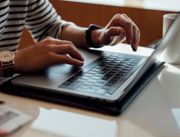 Person seated at the table using laptop.