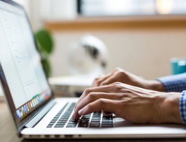 Person typing on laptop keyboard.