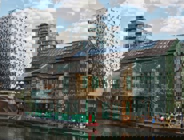 Old and new building side by side in an urban area, with a canal boat in the foreground