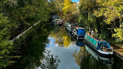 View of canal with narrow boats and autumnal trees.