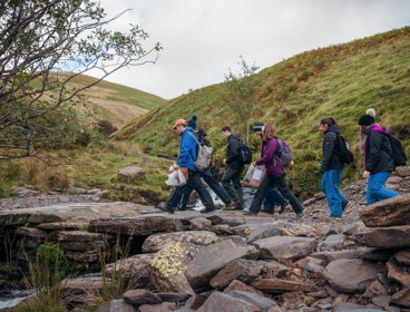 Group of people doing fieldwork. They are walking across rocks in a mountainous region