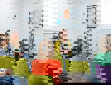 Five female conference delegates seated and having a conversation