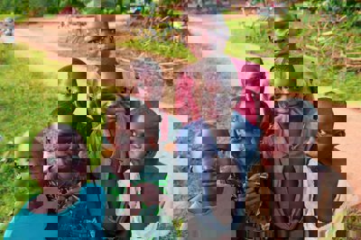 A group of African children standing by a dirt path - their bicycles can be seen in the background