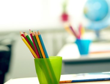 Colouring pencils in green pot in classroom.
